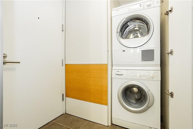 laundry room featuring stacked washing maching and dryer and tile patterned floors