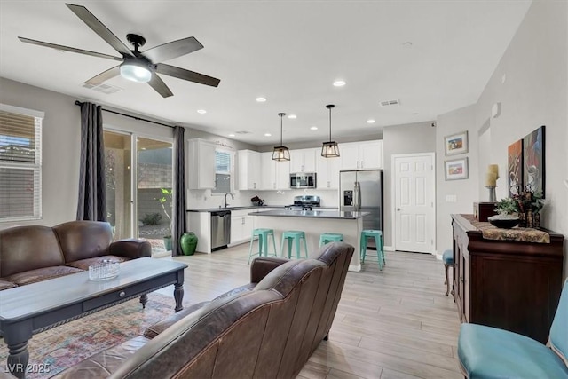 living room with light wood-type flooring, plenty of natural light, and ceiling fan