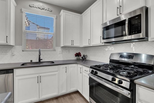 kitchen featuring backsplash, stainless steel appliances, sink, white cabinets, and light hardwood / wood-style floors