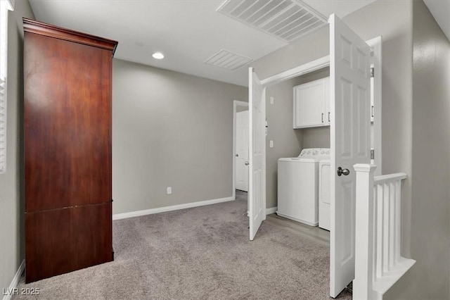 washroom featuring light carpet, washer and dryer, and cabinets