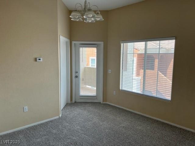 doorway to outside with carpet flooring and a notable chandelier