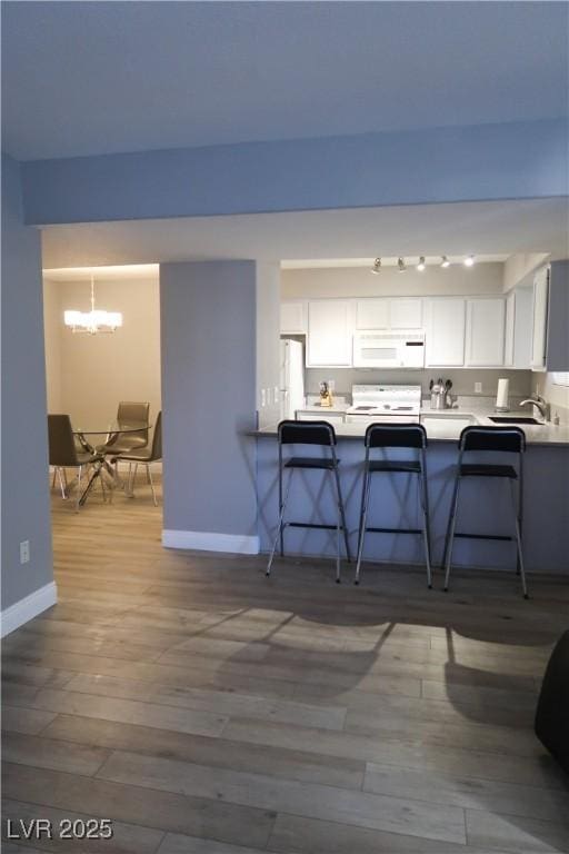 kitchen featuring white cabinetry, a breakfast bar, and white appliances