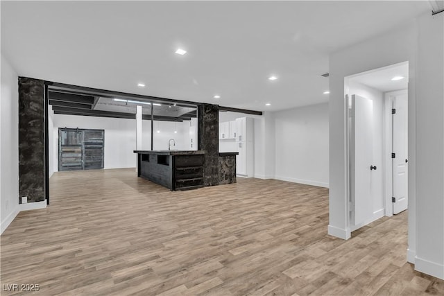 unfurnished living room with indoor wet bar and light wood-type flooring