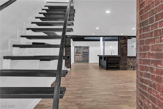 stairway featuring hardwood / wood-style floors, brick wall, and sink