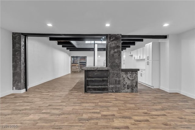 interior space featuring beam ceiling, wood-type flooring, white cabinetry, and sink