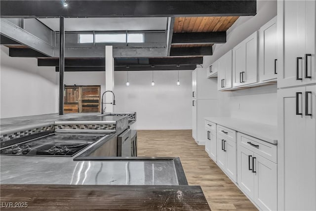 kitchen featuring beam ceiling, sink, wooden ceiling, light hardwood / wood-style floors, and white cabinets