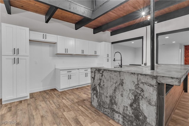 kitchen with beam ceiling, white cabinetry, an island with sink, and wood ceiling