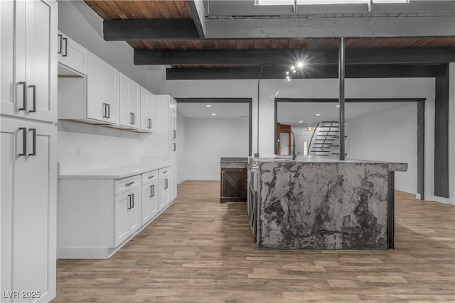 kitchen featuring beam ceiling, white cabinets, wooden ceiling, and light hardwood / wood-style floors