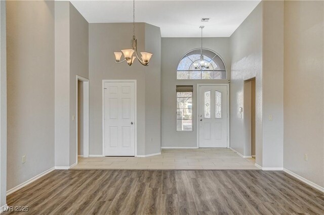 foyer featuring a towering ceiling, an inviting chandelier, and light hardwood / wood-style flooring