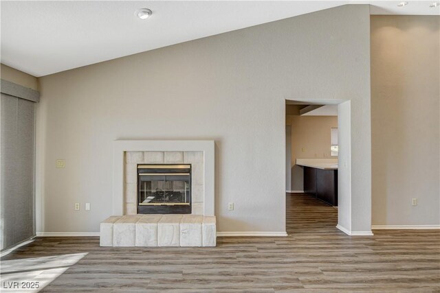 unfurnished living room with light hardwood / wood-style flooring, a fireplace, and lofted ceiling