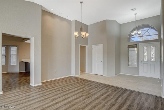 entryway featuring a towering ceiling, light wood-type flooring, and a notable chandelier