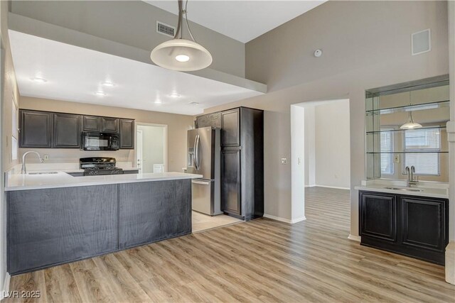 kitchen with light hardwood / wood-style floors, sink, black appliances, and kitchen peninsula