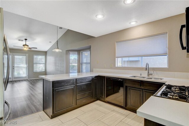 kitchen with vaulted ceiling, pendant lighting, black dishwasher, sink, and kitchen peninsula