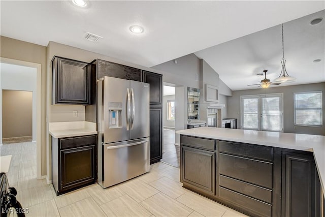 kitchen with pendant lighting, lofted ceiling, ceiling fan, stainless steel refrigerator with ice dispenser, and dark brown cabinets