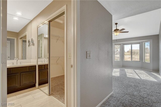 interior space with vanity, a textured ceiling, and ceiling fan