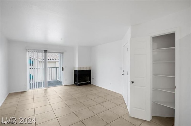 unfurnished living room featuring a multi sided fireplace and light tile patterned floors