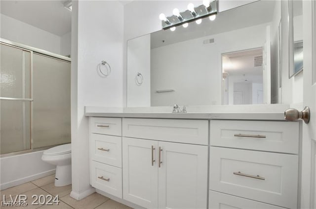 full bathroom featuring tile patterned flooring, vanity, toilet, and bath / shower combo with glass door