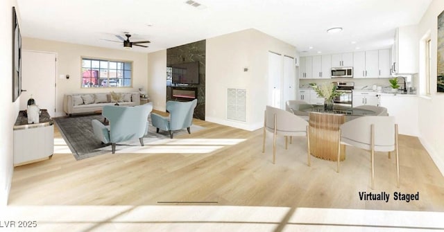 kitchen featuring white cabinetry, ceiling fan, sink, stainless steel appliances, and light hardwood / wood-style flooring