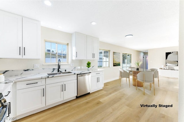 kitchen featuring light stone counters, stainless steel dishwasher, sink, light hardwood / wood-style flooring, and white cabinetry