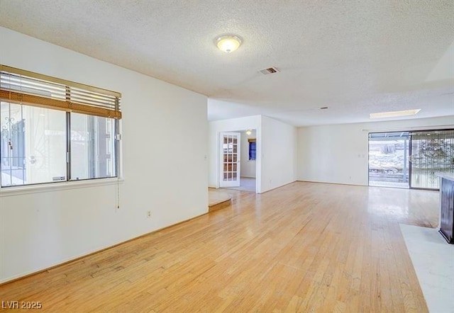 empty room with light hardwood / wood-style floors and a textured ceiling