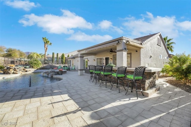 view of patio / terrace featuring ceiling fan, pool water feature, and exterior bar