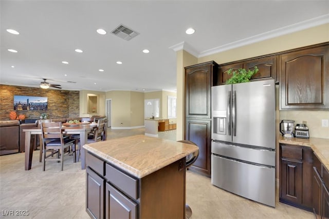 kitchen featuring crown molding, stainless steel fridge with ice dispenser, ceiling fan, a kitchen island, and dark brown cabinetry