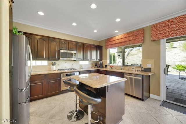 kitchen with a breakfast bar, a kitchen island, ornamental molding, and appliances with stainless steel finishes