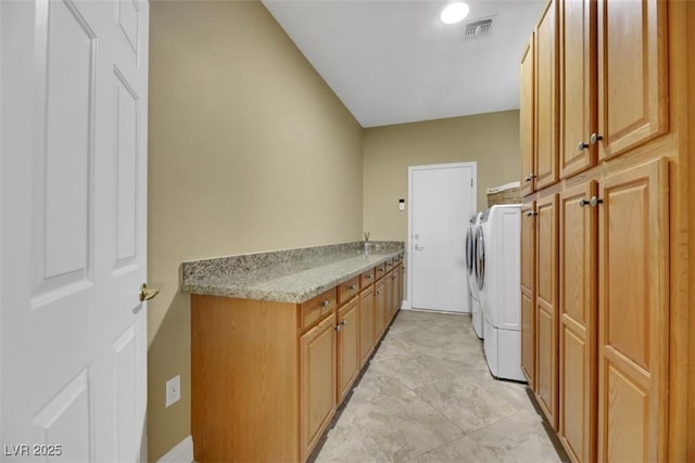 clothes washing area featuring separate washer and dryer and cabinets