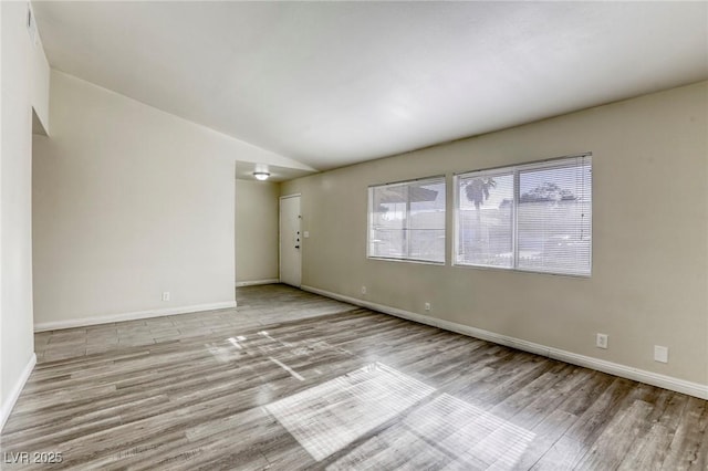 empty room featuring lofted ceiling and light wood-type flooring