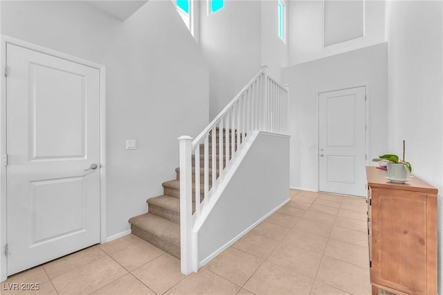 stairway with tile patterned flooring and a towering ceiling