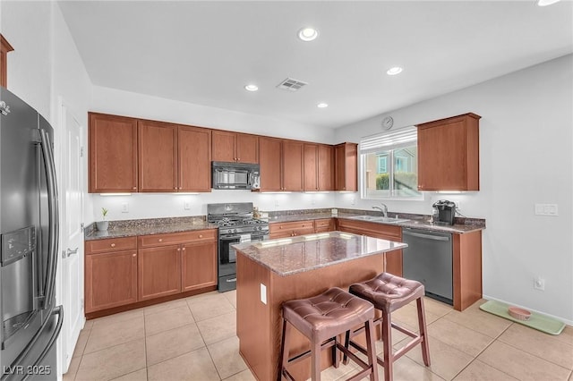 kitchen featuring sink, black appliances, dark stone countertops, a center island, and a breakfast bar area