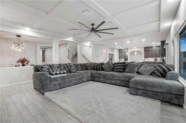 living room with light hardwood / wood-style floors, beamed ceiling, coffered ceiling, and ceiling fan with notable chandelier