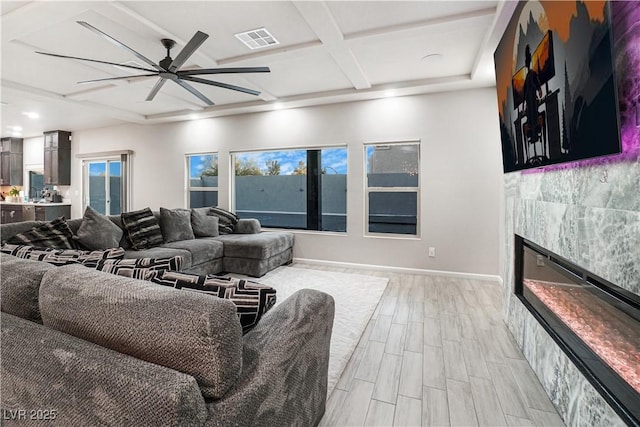 living room featuring a tile fireplace, beamed ceiling, ceiling fan, light hardwood / wood-style floors, and coffered ceiling