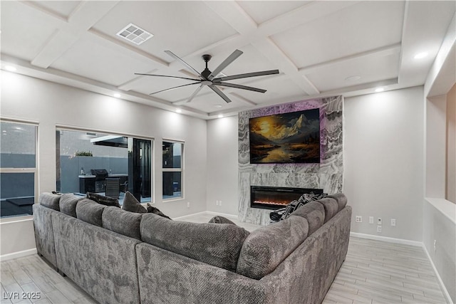 living room featuring a high end fireplace, ceiling fan, and coffered ceiling