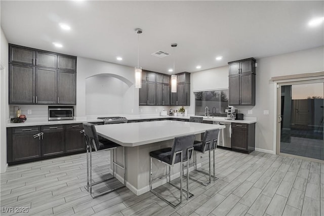 kitchen featuring a kitchen breakfast bar, pendant lighting, a center island, and appliances with stainless steel finishes