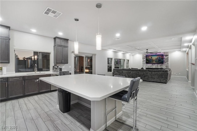 kitchen with sink, a kitchen breakfast bar, ceiling fan, a kitchen island, and pendant lighting