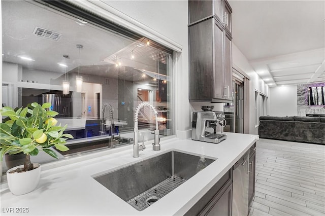 kitchen with sink, hanging light fixtures, stainless steel dishwasher, and dark brown cabinetry