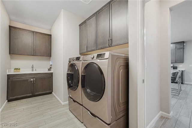 clothes washing area with cabinets, separate washer and dryer, and sink