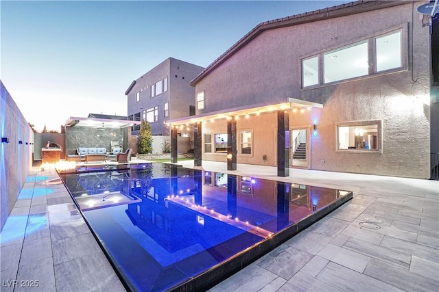 pool at dusk featuring an in ground hot tub and a patio area