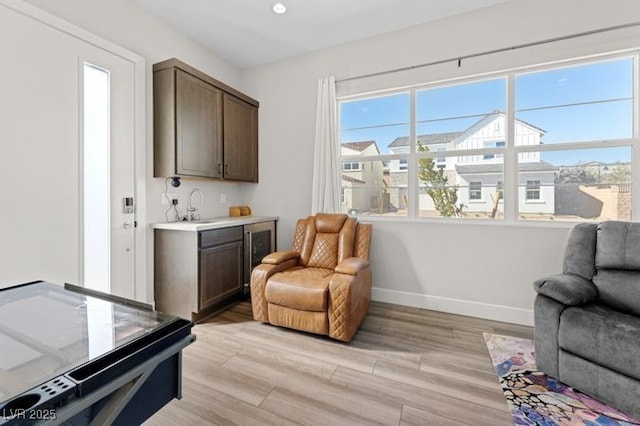 sitting room featuring baseboards, light wood-type flooring, and a healthy amount of sunlight