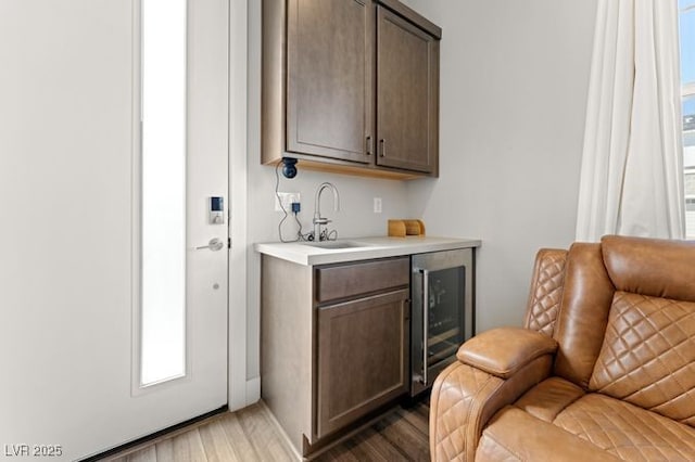 bar featuring a sink, a healthy amount of sunlight, beverage cooler, and dark wood-type flooring