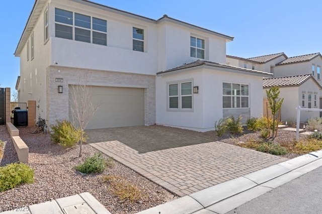 view of front facade featuring a garage, decorative driveway, and stucco siding