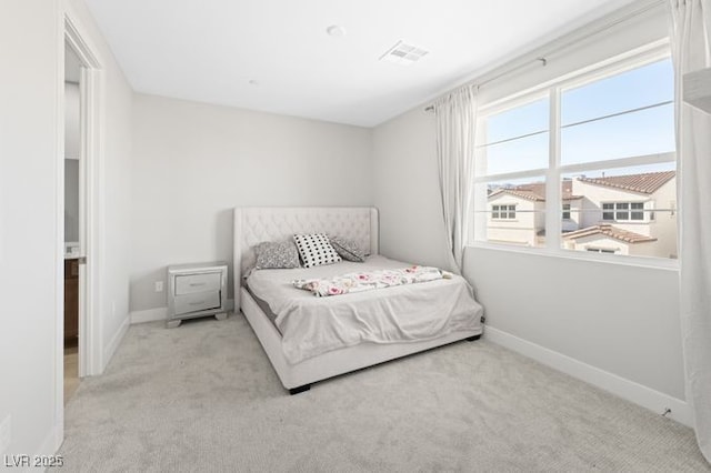 bedroom featuring baseboards, visible vents, and light colored carpet