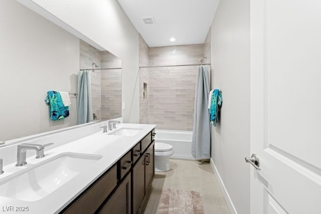 full bath featuring double vanity, shower / bath combo with shower curtain, a sink, and toilet