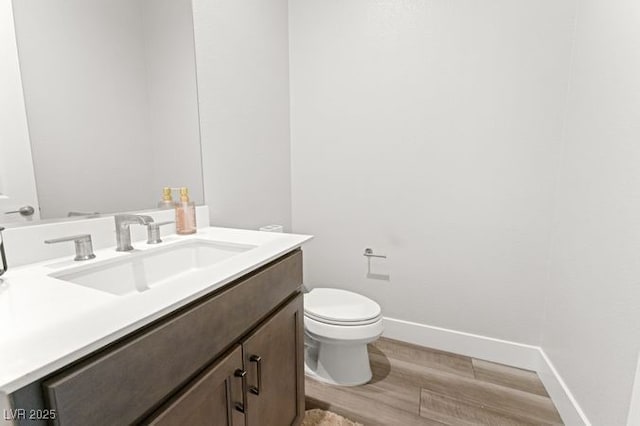 bathroom featuring wood finished floors, vanity, toilet, and baseboards