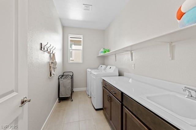 laundry area featuring cabinet space, light tile patterned floors, baseboards, independent washer and dryer, and a sink