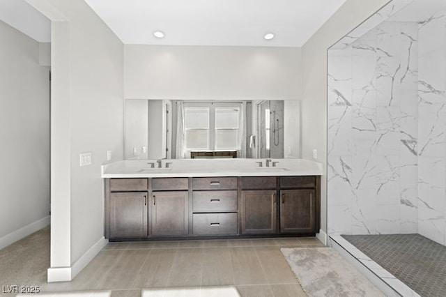 bathroom with double vanity, recessed lighting, a sink, a tile shower, and baseboards