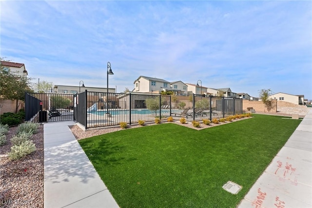 view of yard featuring a community pool, fence, and a residential view