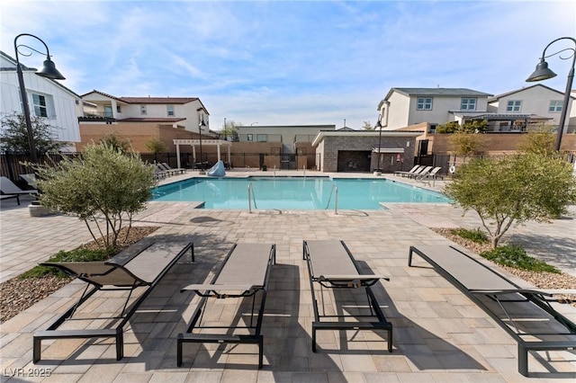 community pool featuring a patio area, a residential view, and fence