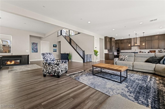 living room featuring recessed lighting, baseboards, dark wood finished floors, and a glass covered fireplace